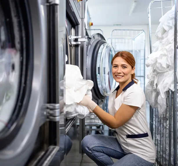 Laundry Worker putting clothes into a machine